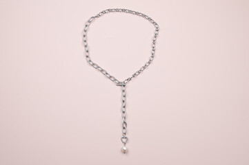 Silver chain with white baroque pearl pendant on pastel pink background