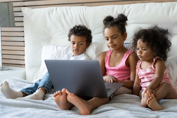 Cute children sister brother watching online cartoons on laptop before bedtime