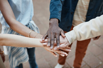 Close up of multi-ethnic group of young people stacking hands outdoors and celebrating friendship, copy space