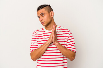 Young venezuelan man isolated on white background praying, showing devotion, religious person looking for divine inspiration.