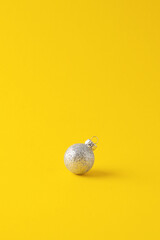 Christmas yellow minimal background with grey ball. Close up, copy space