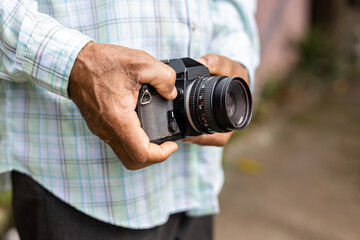 Fototapeta premium Close-up view of the elderly hand holding an old film camera.