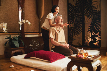 Asian woman doing traditional massage for grizzled man