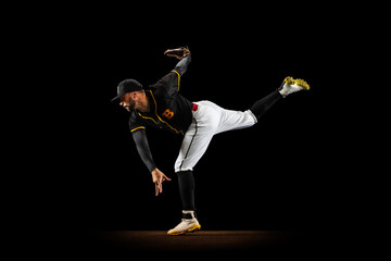 Professional baseball player, pitcher in sports uniform and equipment practicing isolated on a black studio background. Team sport concept