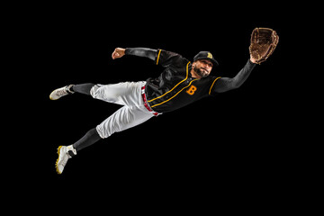 Flying. Baseball player, catcher in sports uniform and equipment practicing isolated on a black...