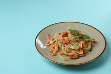 Plate of tasty shrimp pasta on blue background