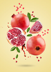 A ripe pomegranate with seeds and leaves flying in the air. Background with pomegranate fruit.