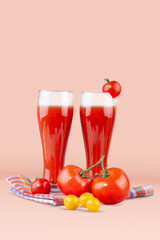Two glasses with tomato juice and a small tomato on a bright background.
