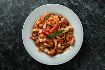 Plate of shrimp pasta on black smokey background