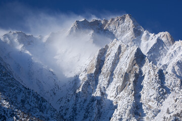 Winter landscape of the Eastern Sierra Nevada Mountains covered in snow and framed by a clear blue sky, near Lone Pine, California, USA