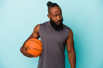 African american man playing basketball isolated on blue background confused, feels doubtful and unsure.
