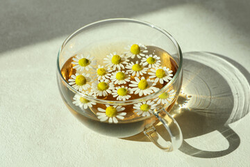 Cup of chamomile tea on white textured table