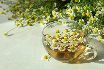 Cup of chamomile tea on white textured table