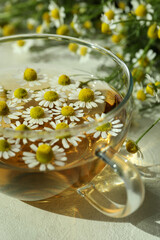 Cup of chamomile tea on white textured table