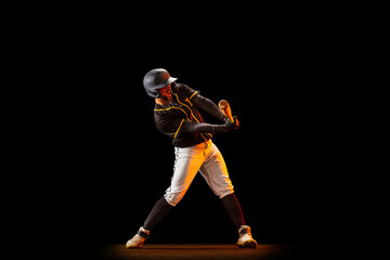 Fototapeta na wymiar Professional baseball player, pitcher in sports uniform and equipment playing baseball isolated on black studio background in neon light. Team sport concept