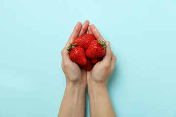 Female hands hold fresh strawberry on blue background