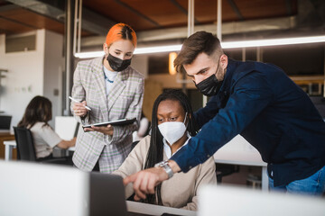 Company of multiethnic colleagues in masks working together in office