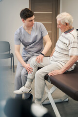 Obraz premium Worried doctor feeling senior citizen leg with hands