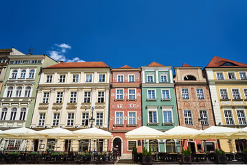 Plakat facades of historic tenements houses and umbrellas of the restauranton the Old Market Square
