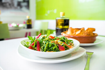 Green arugula salad, chopped strawberries, walnuts and parmesan cheese in flakes, olive oil and vinegar vinaigrette