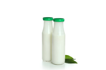 Bottles of milk and leaves isolated on white background