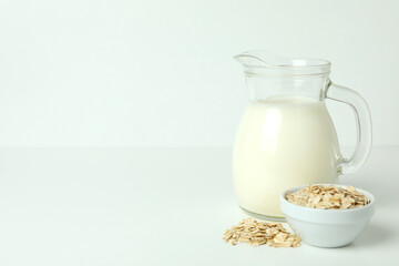Pitcher of milk and cereals on white background