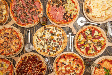 Set of whole pizza on wooden table. Barbecue, mushrooms with ham, vegetable with pineapple, cheese and guanciale, forks and pizza cutters