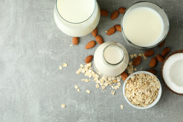 Concept of vegan milk on gray textured background, top view