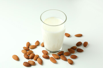 Glass of milk and almonds on white background