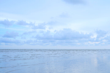 white clouds in the evening blue sky with calm sea waves The beach looks beautiful.