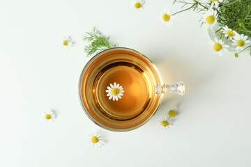 Cup of chamomile tea and ingredients on white background