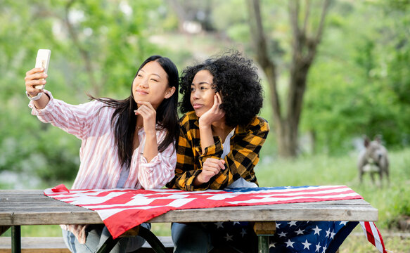LGBT multiracial girlfriends taking selfie on smartphone in forest