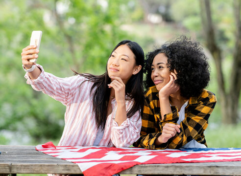 LGBT multiracial girlfriends taking selfie on smartphone in forest