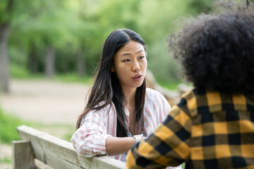 Lesbian couple of multiethnic women holding hands near lake