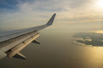 Fototapeta na wymiar aircraft wing over ocean and island