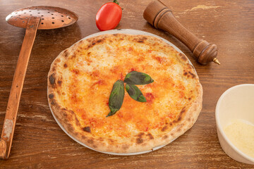 Pizza margarita cooked in an Italian restaurant with vintage utensils on wooden table