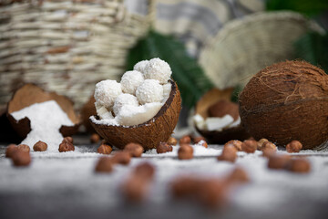 Coconut candy, balls, coconuts and hazelnuts on a rustic wooden surface