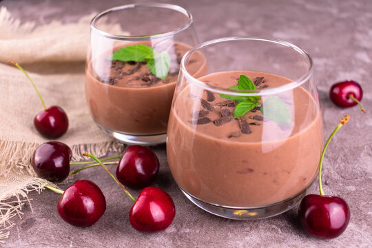 Two glasses with chocolate cherry smoothies on a gray background.