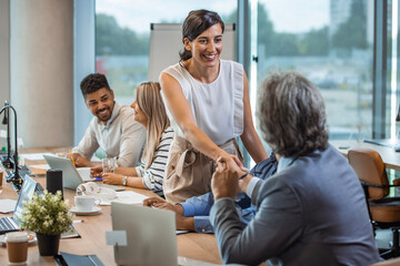 Welcome to our team! Top view of business people in smart casual wear shaking hands while working in the creative office. Business handshake and business people. 