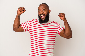 African american man with beard isolated on pink background raising fist after a victory, winner concept.