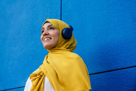Happy muslim woman listening to music in headphones