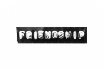 Embossed letter with word friendship in black banner on white paper background