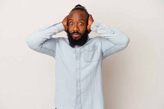 African american man with beard isolated on pink background covering ears with hands trying not to hear too loud sound.