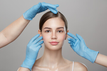 People, cosmetology, plastic surgery and beauty concept - surgeon or beautician hands touching woman face over gray background. - 443429194