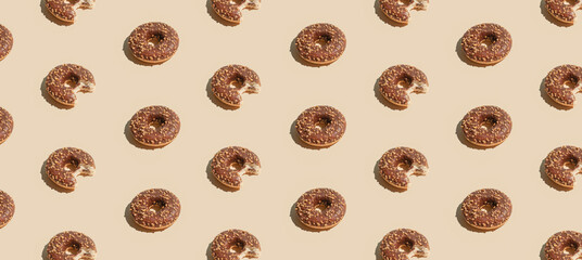 Creative summer vibes concept with fresh brown chocolate doughnuts on pastel bright beige...