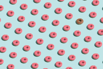 Creative optimistic summer vibes idea with pink and brown chocolate donuts on bright blue background. Minimalistic irregular pattern arrangement, colorful sweet food concept.