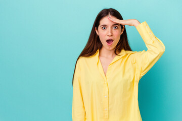 Young caucasian woman isolated on blue background shouts loud, keeps eyes opened and hands tense.