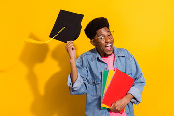 Photo of happy brunette dark skin man hold hat graduate wear denim shirt notes glasses isolated on...