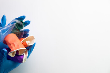 Save environment. Plastic pollution. Waste reduction. Ecology problem. Unrecognizable female hands in surgical gloves holding colorful plastic litter isolated on white copy space background.