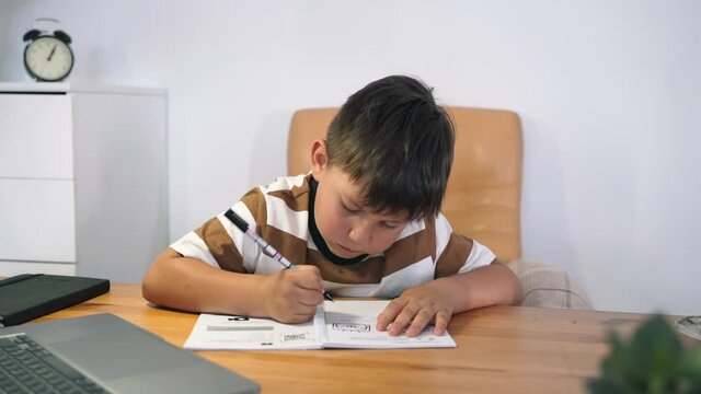 A boy performs a task in an online lesson. The child communicates online while sitting at the table. The child learns at the computer. Home education. Online training Self-isolation Slow motion